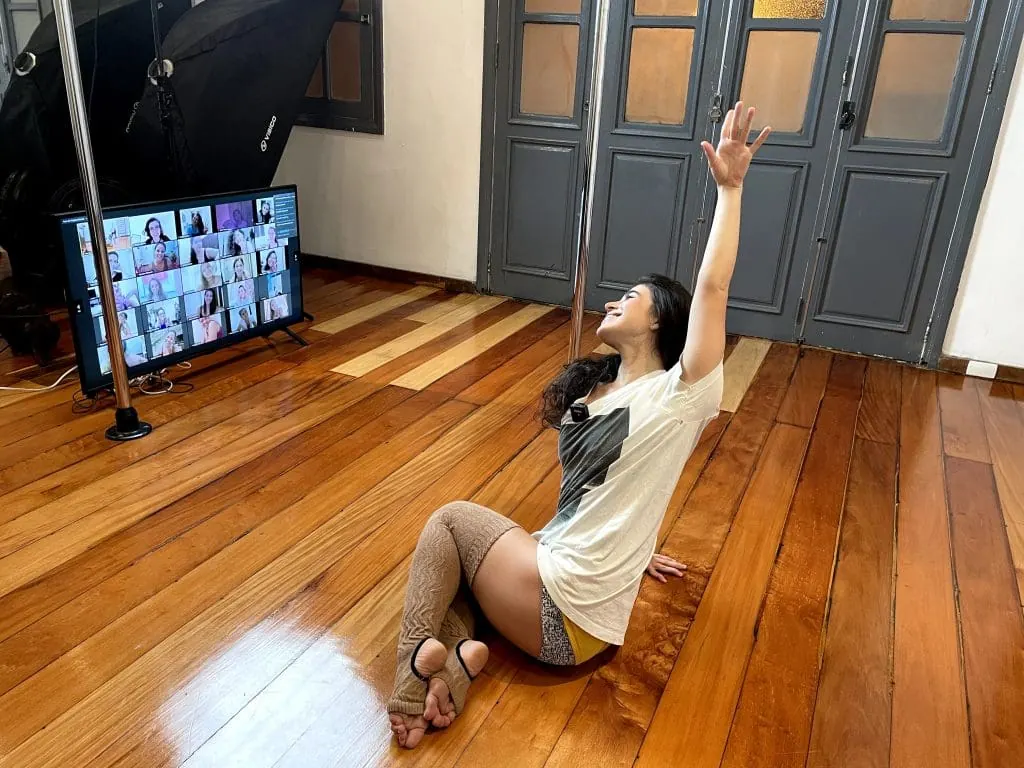 Aluna praticando pole dance em casa acompanhando aula online